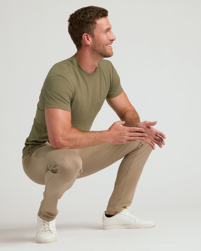 Man wearing Khaki Slim Comfort Knit Chino Pant, squatting in profile.