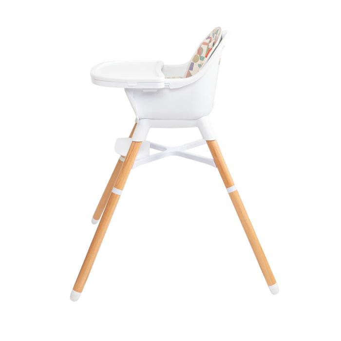 The Nuby 4-in-1 Multi-Use High Chair | White Geometrics features light wood legs, a footrest, and tray. A colorful patterned cushion adds comfort as this versatile high chair grows with your child. Photographed on a plain white background.