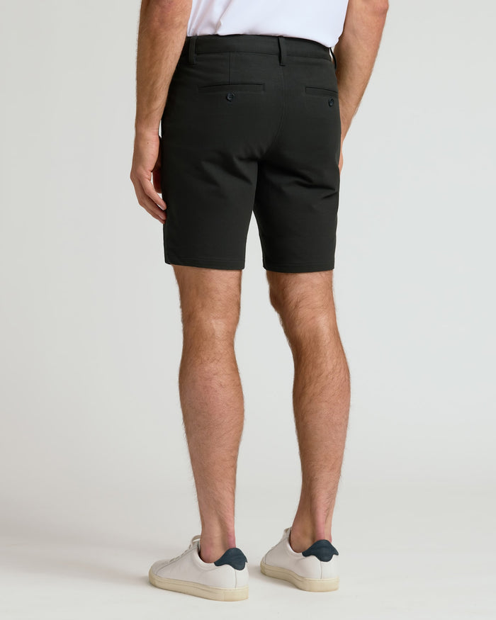 Man wearing 7 Black Chino Shorts 2.0 and white sneakers, back view.