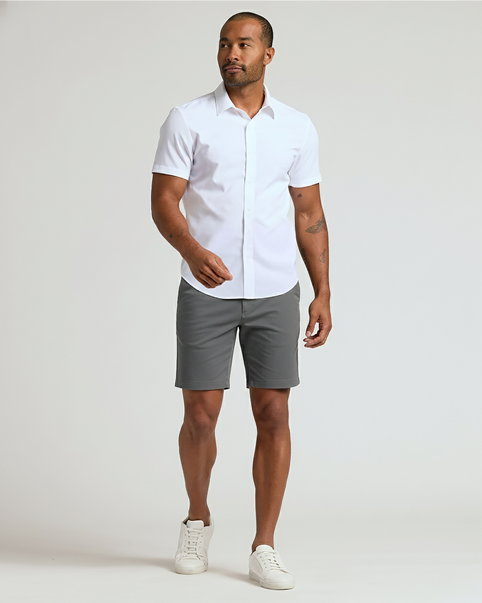 Man wearing 7 Carbon Chino Shorts 2.0, white shirt, white sneakers.