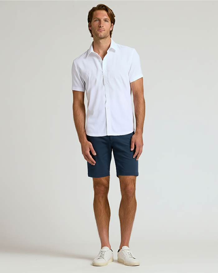 Man wearing 7 Navy Chino Shorts 2.0, white shirt, sneakers.