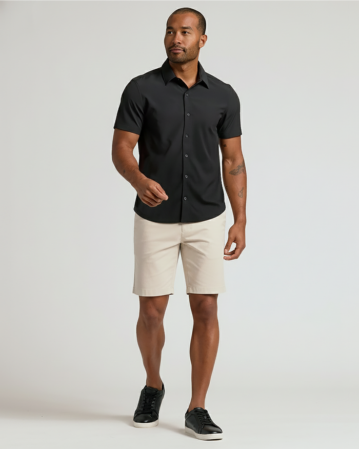 Man wearing 7 Sandstone Chino Shorts 2.0, black shirt, sneakers.