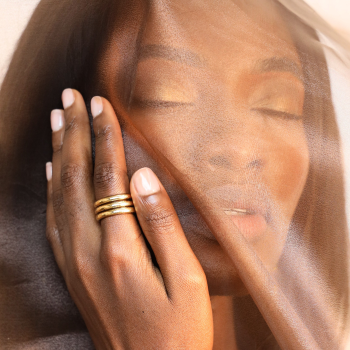 Aura All Weather Rings (Set of 3) showcased on a hand, with a softly veiled face in the background.