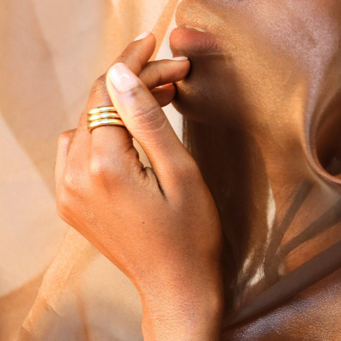 Aura All Weather Rings (Set of 3) worn on finger, showcasing their elegance against soft fabric backdrop.