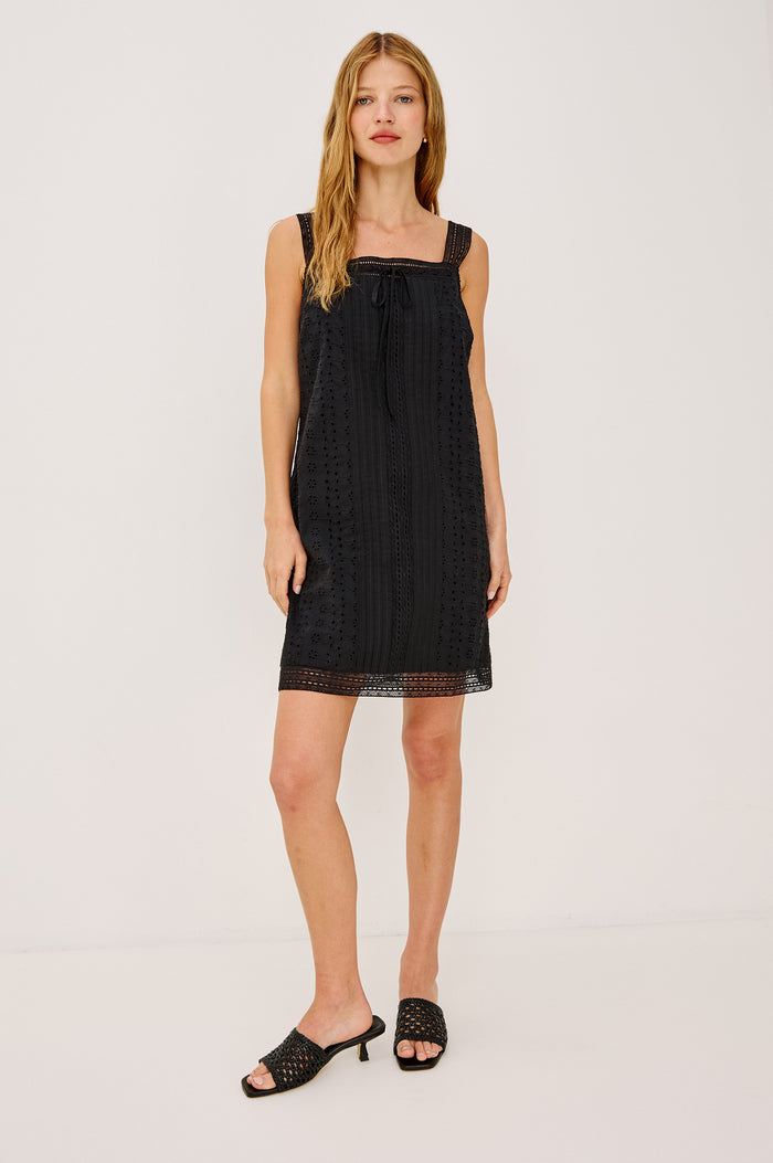 Beckton Mini Shirt Dress With Square Neckline, Eyelet Embroidery, Front Pintucks, Center-Front Ties, and Lace Shoulder Straps in Black Colorway - Full Body Front View Featured on Model