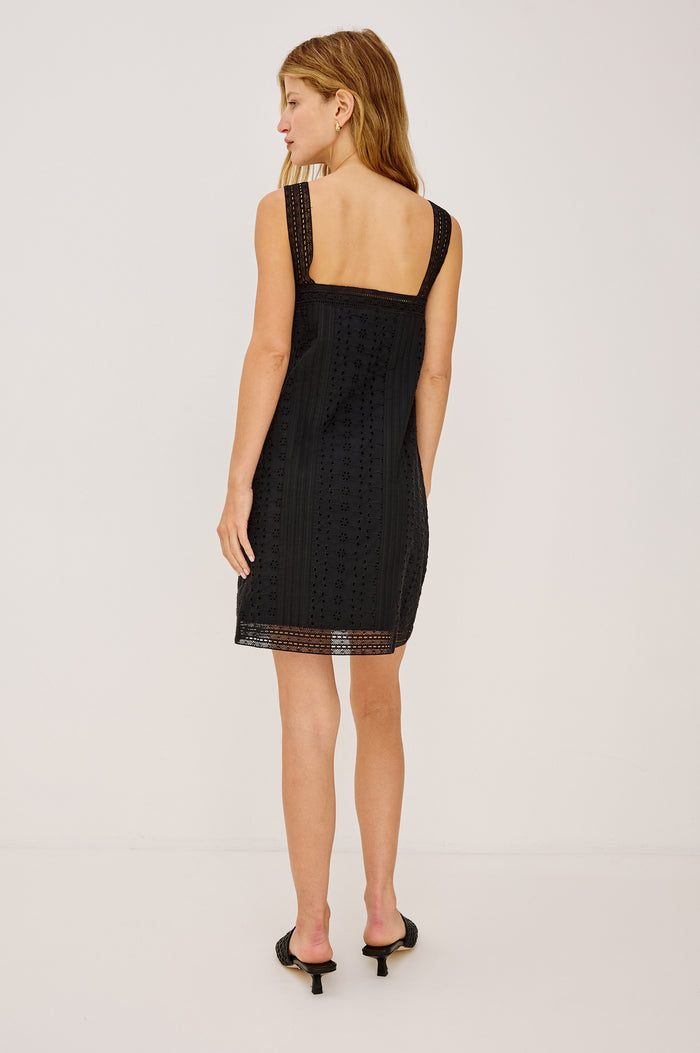 Beckton Mini Shirt Dress With Square Neckline, Eyelet Embroidery, Front Pintucks, Center-Front Ties, and Lace Shoulder Straps in Black Colorway - Full Body Back View Featured on Model