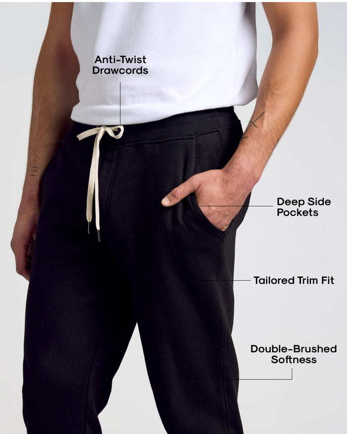 Man wearing Black Fleece French Terry Joggers showcasing features: anti-twist drawcords, deep pockets, tailored trim, double-brushed softness.