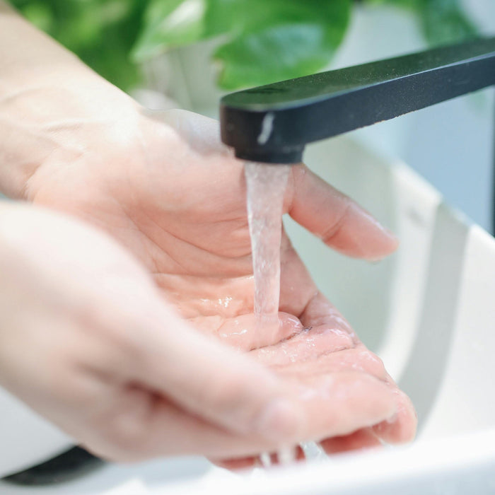 white hands at white sink black faucet running water dermal essentials medical grade skincare