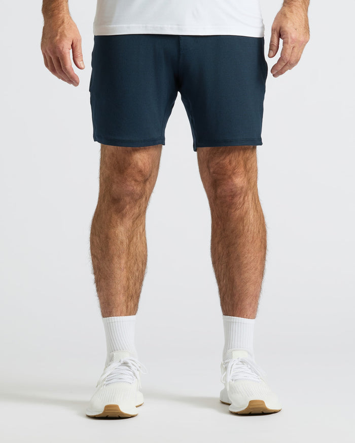 Man wearing Dark Heather Navy Active Comfort Shorts, white socks, running shoes.