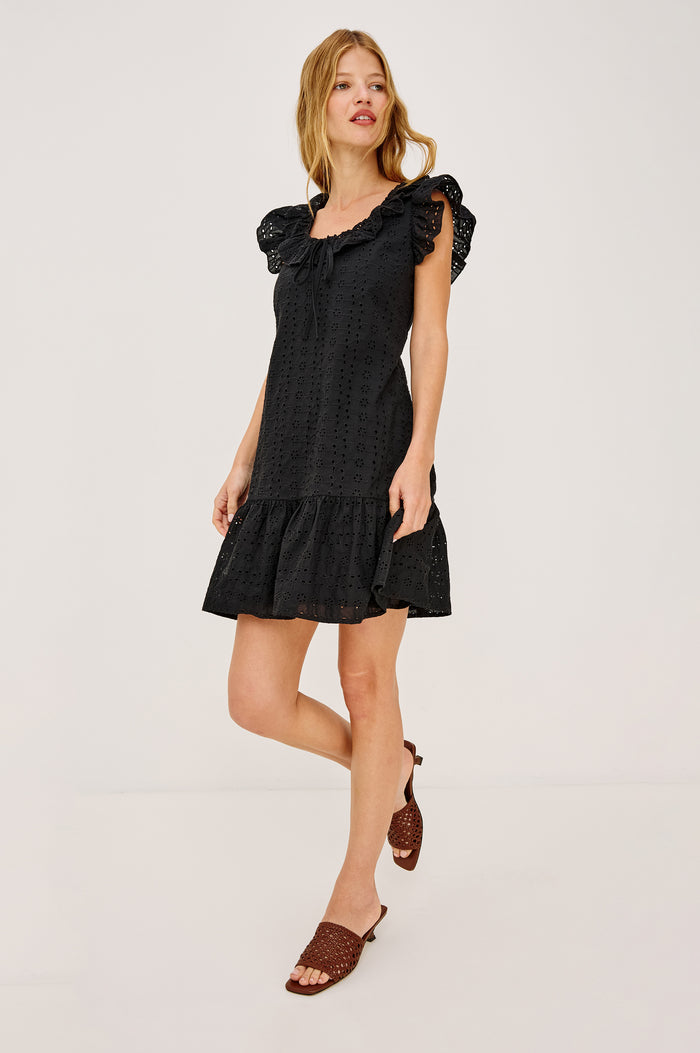 Essie Mini Dress in Cotton Voile With Eyelet Detailing, A-Line Silhouette, Wide Scoop Neckline With Ruffle Trim, Flutter Sleeves, and is Fully Lined in Black Eyelet Colorway - Upper Body Front View Featured on Model