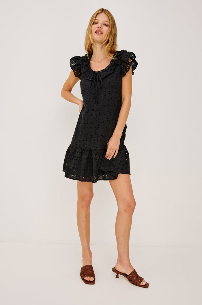Essie Mini Dress in Cotton Voile With Eyelet Detailing, A-Line Silhouette, Wide Scoop Neckline With Ruffle Trim, Flutter Sleeves, and is Fully Lined in Black Eyelet Colorway - Full Body Front View Featured on Model