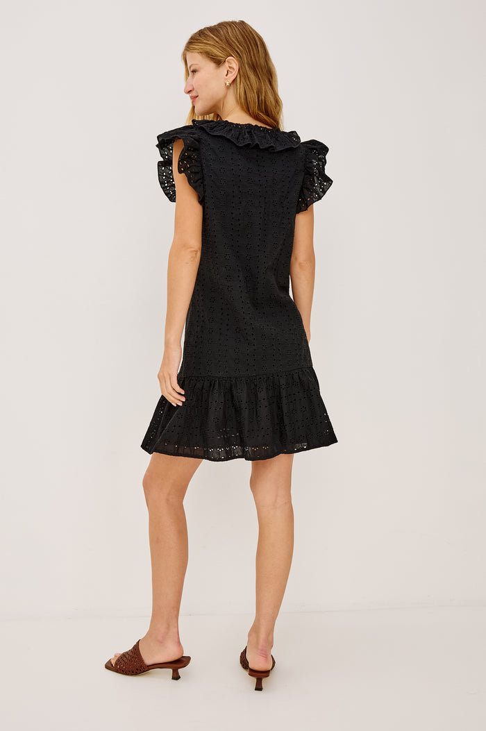 Essie Mini Dress in Cotton Voile With Eyelet Detailing, A-Line Silhouette, Wide Scoop Neckline With Ruffle Trim, Flutter Sleeves, and is Fully Lined in Black Eyelet Colorway - Full Body Back View Featured on Model