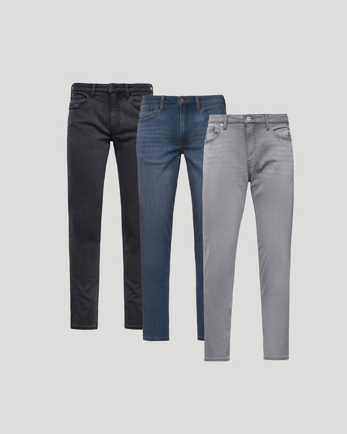 Three pairs of men's jeans in black, indigo, and gray colors displayed standing side by side, showcasing the Gray Medium Indigo Slim Comfort Stretch Jeans 3-Pack.