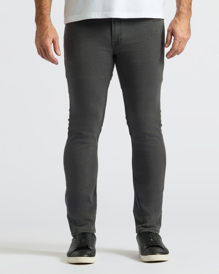 Gray Wash Slim Comfort Stretch Jeans with black sneakers and white shirt hem.
