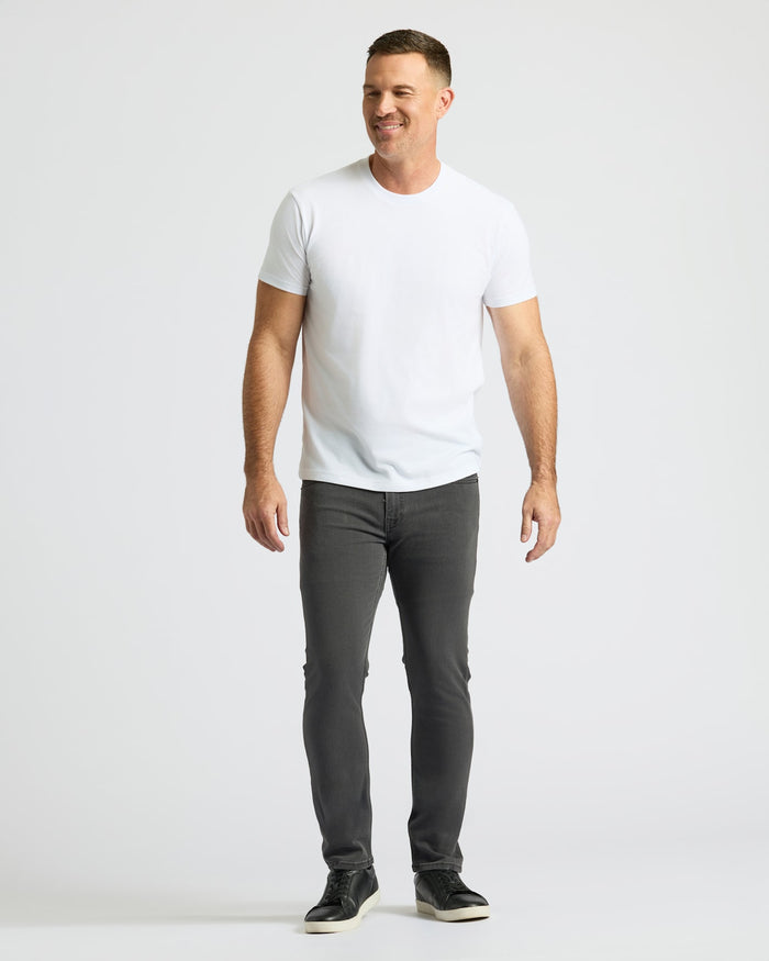 Man wearing Gray Wash Slim Comfort Stretch Jeans, white t-shirt, black sneakers.