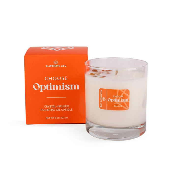 I Choose Optimism Candle | Aluminate Life with crystal-infused essential oil, presented in a clear glass jar alongside its bright orange packaging for wellness and relaxation.