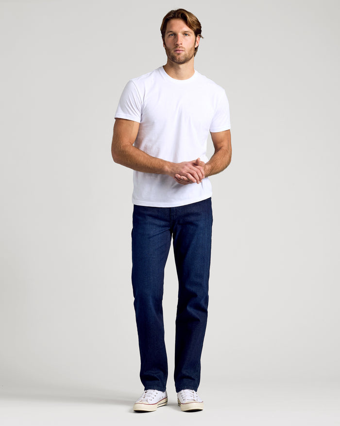 Man wearing Indigo Rinse Straight Authentic Denim Jeans, white T-shirt, canvas sneakers.