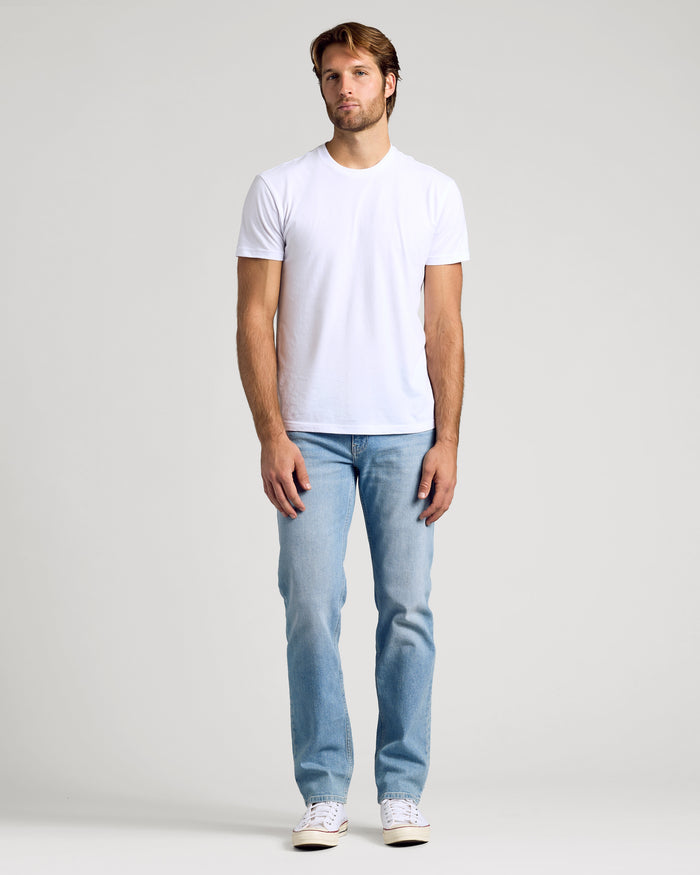 Man wears Light Indigo Wash Straight Authentic Denim Jeans.