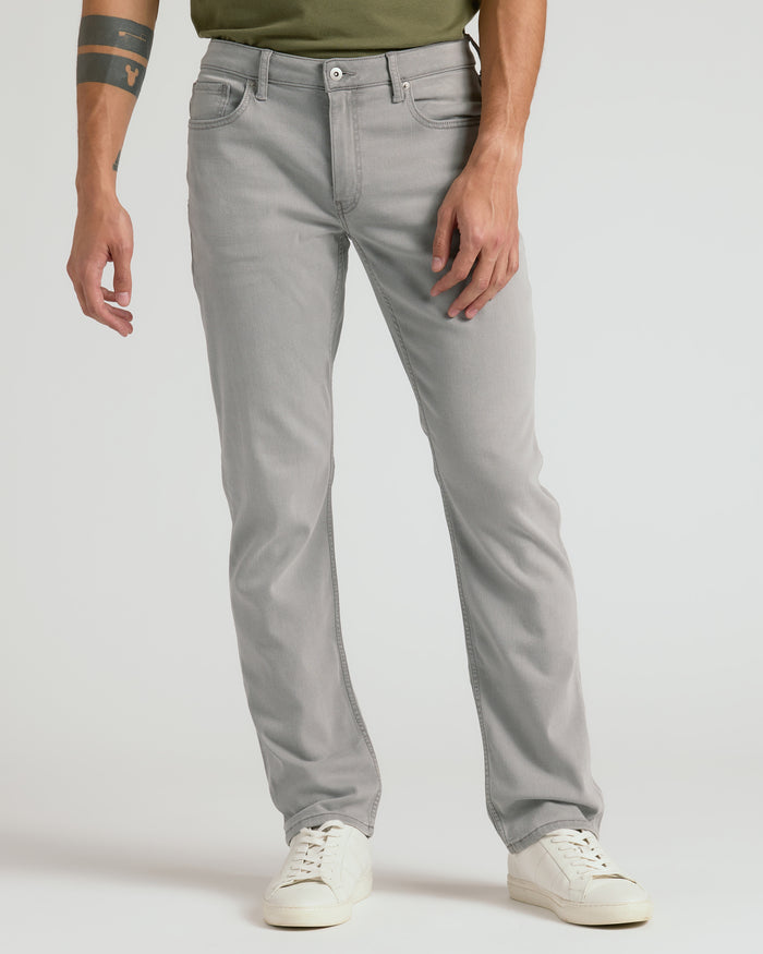 Medium Gray Wash Straight Comfort Stretch Jeans with white sneakers and tattooed forearm.