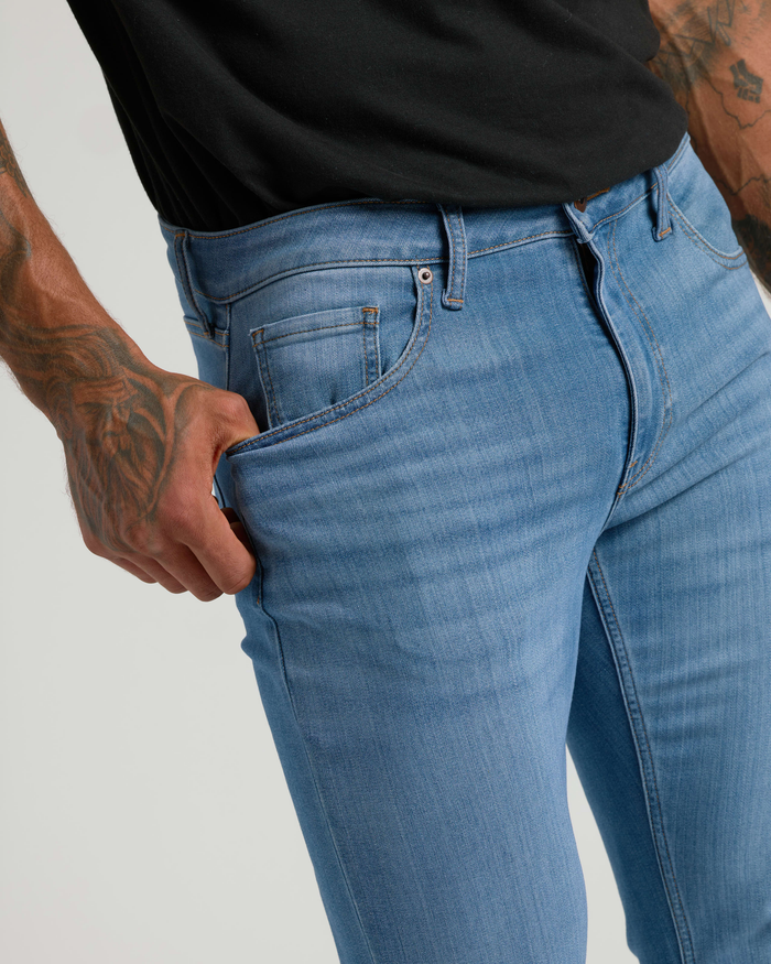 Close-up of a man wearing Medium Indigo Wash Slim Comfort Stretch Jeans, showing a fitted silhouette and soft stretch fabric for comfort.