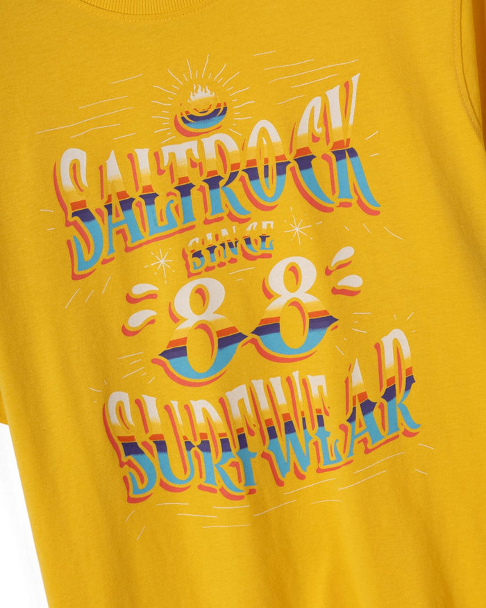 The Saltrock Mex Logo Men's T-Shirt in yellow features colorful retro "Saltrock Since 88 Surfwear" text with decorative graphics, classic crew neckline, and is made from 100% cotton.