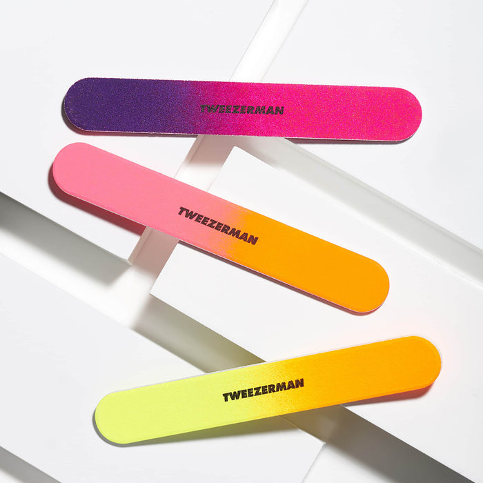 Three colorful gradient nail files in purple to pink, pink to orange, and yellow to orange shades with Tweezerman branding, part of the Neon Filemate Set | Tweezerman.