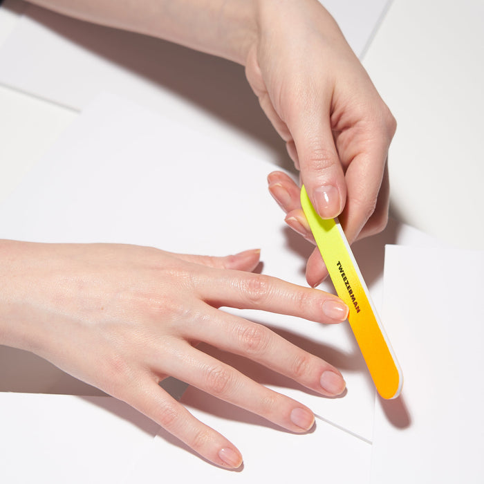 Person using a neon gradient nail file on fingernails, showcasing the Neon Filemate Set | Tweezerman for precise nail care and grooming.