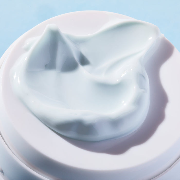 Close-up of a smooth, creamy texture of Refreshing Water Cream Organic Face Sunscreen SPF 50 | COOLA in soft light, highlighting its hydrating skincare formula.