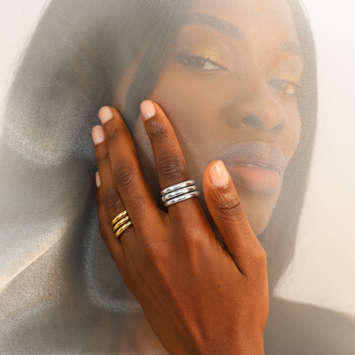 A close-up of a hand model showcasing Silver All Weather Rings (Set of 3) with gold and silver stackable rings.