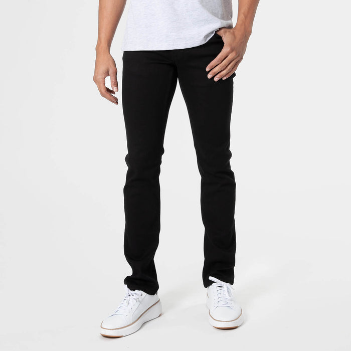 Man wearing black slim fit jeans paired with white sneakers and a white t-shirt, showcasing the Slim Comfort Stretch Jeans 3-Pack as a versatile men's basics essential.