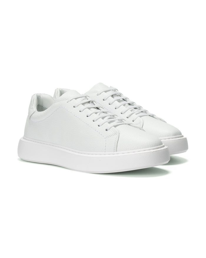 A pair of white leather low-top sneakers with matching white laces and thick white platform soles, shown on a clean white background.