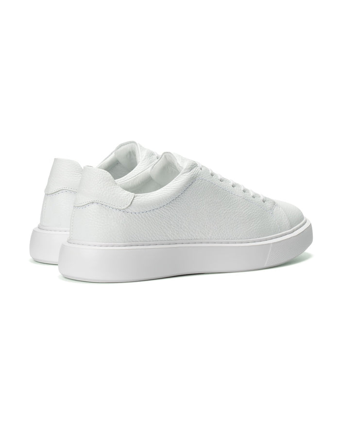 A pair of low-top white leather sneakers shown from a side-rear angle on a clean white background.